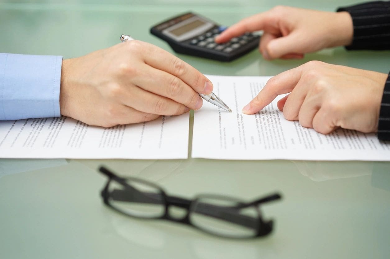 Hands reviewing documents with calculator nearby.