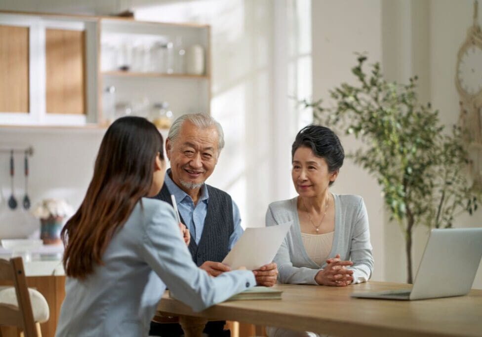 Three people discussing documents at table.